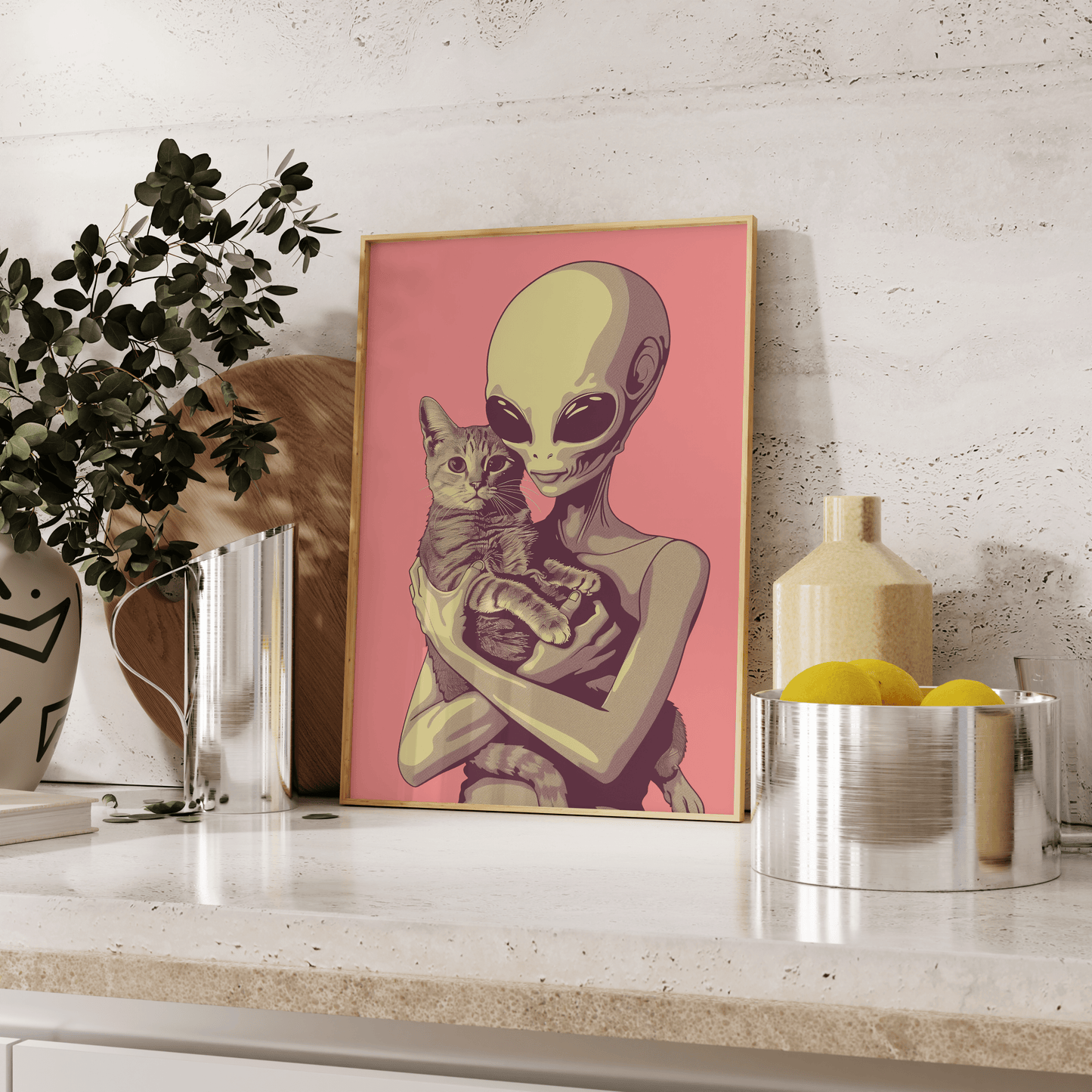 Paw Prints framed poster of a retro alien cradling a tabby cat in a pink background, leaning against the kitchen counter.