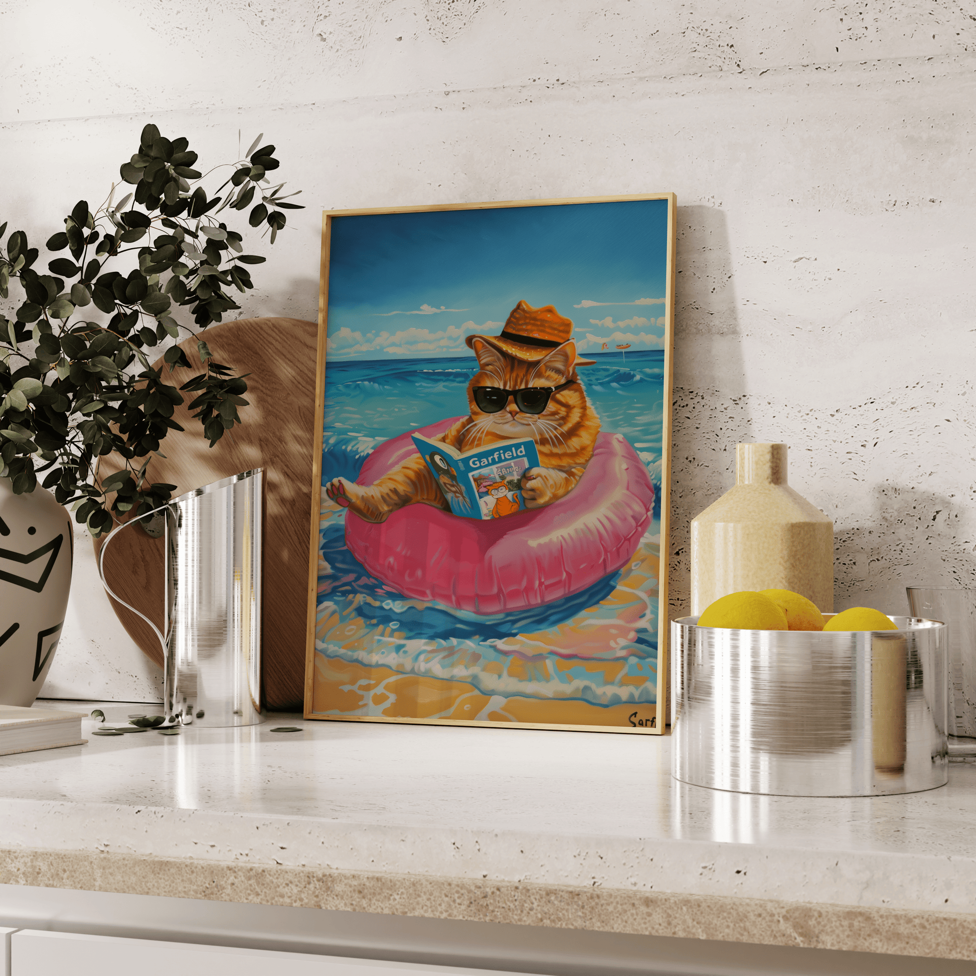 Framed poster of a cat wearing a straw hat reading Garfield, sitting on the beach, leaning against the kitchen counter
